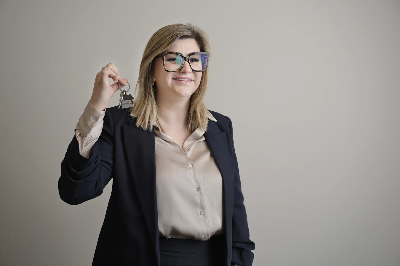 Real estate agent in a blazer holding up a set of house keys